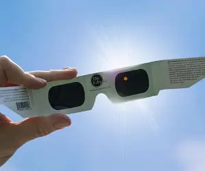 lentes para eclipse solar, puesto en mano, viendo al sol a través de los lentes para eclipse
